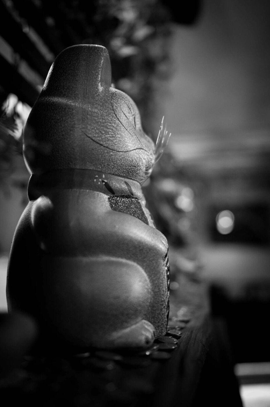 A lucky cat figurine on the counter, in black and white