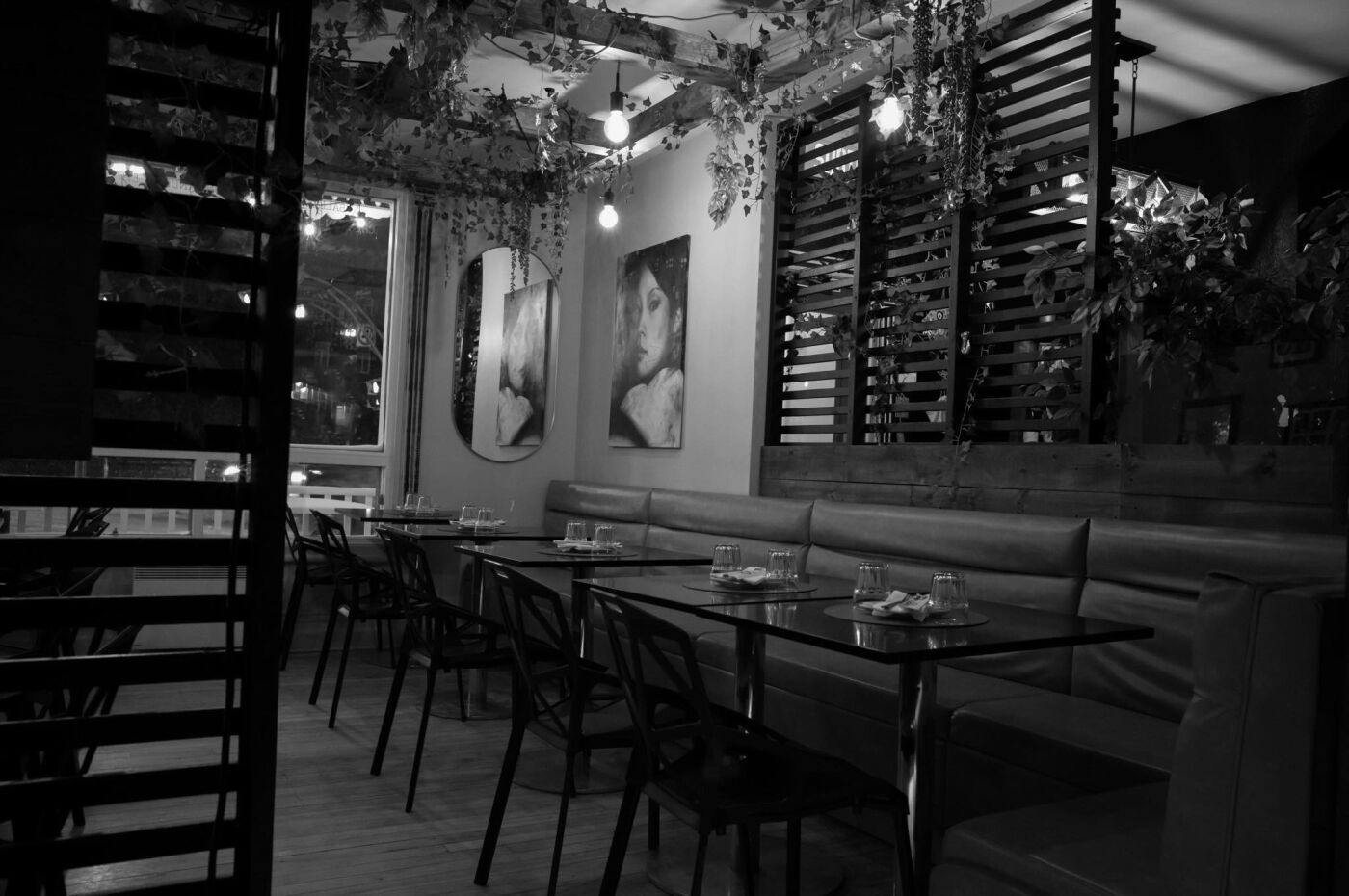 The dining room in black and white: banquettes, framed portraits, hanging plants