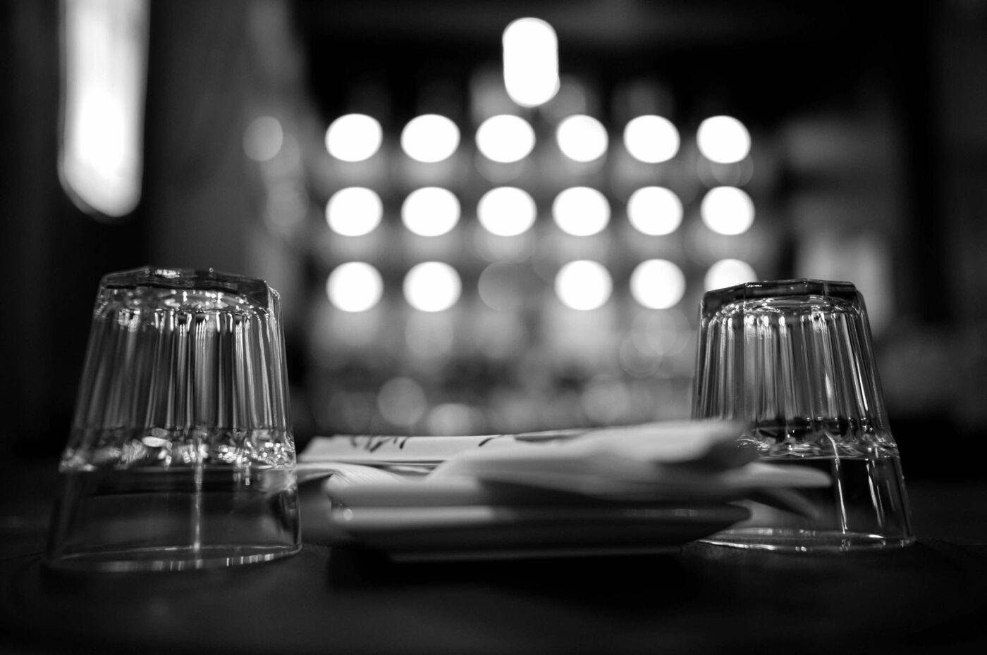 Upturned glasses on a table, the glowing bar blurred behind