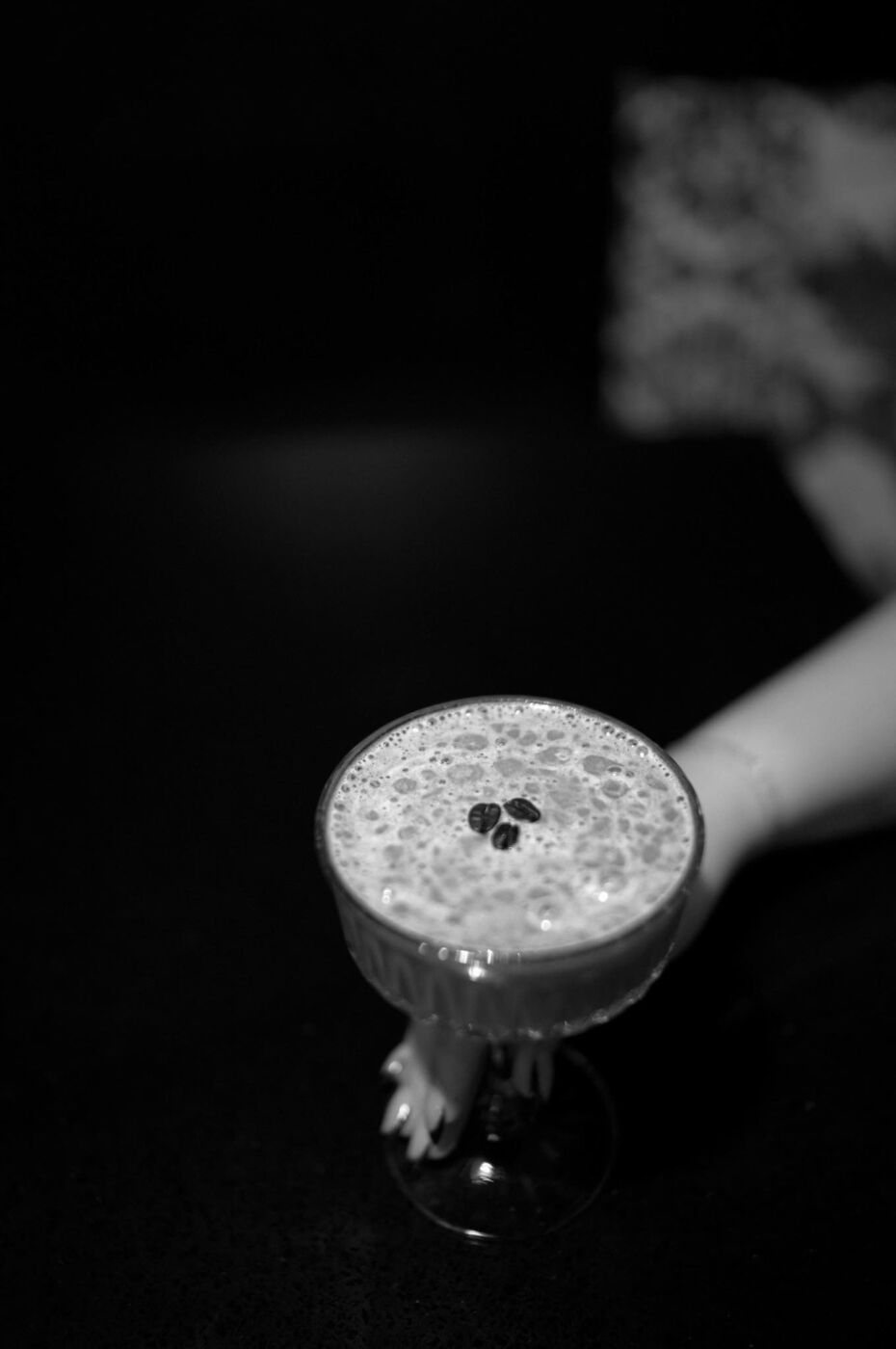 A frothy cocktail held in the half-light